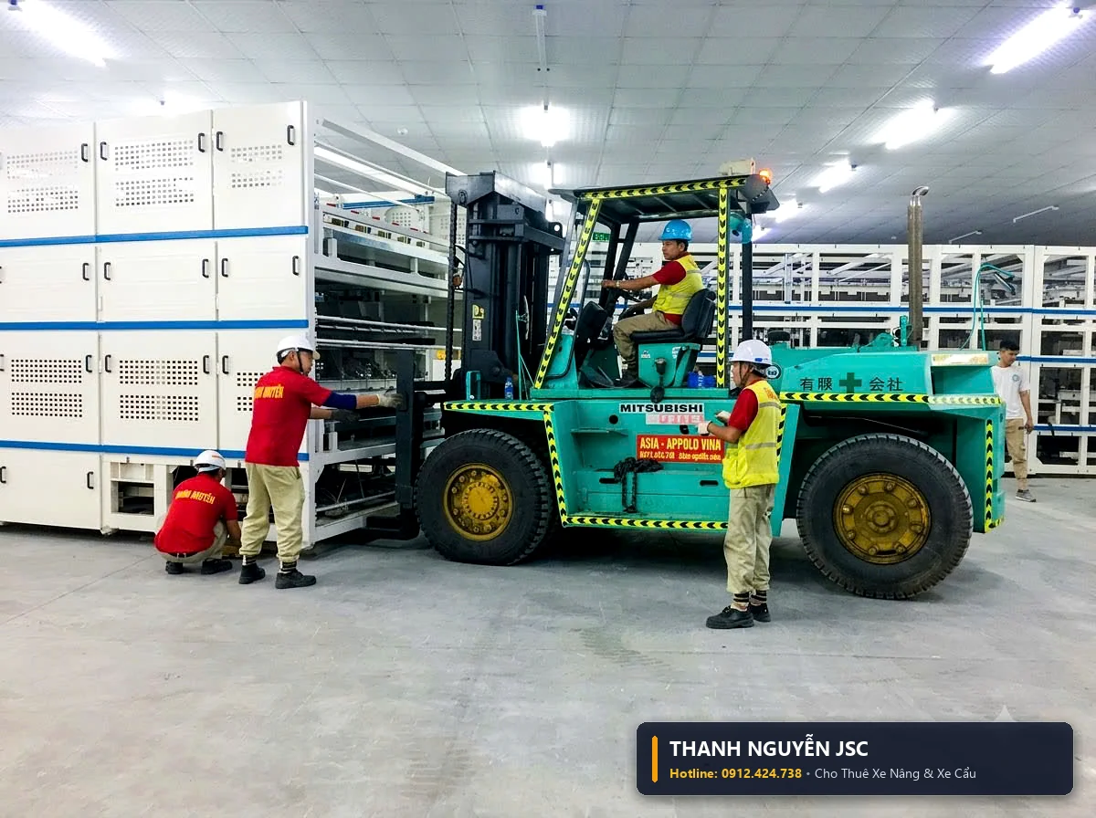 Xe nâng hàng đưa khối máy móc công nghiệp áp sát dây chuyền tự động hóa với sự điều phối của công nhân THÀNH HUY HOÀNG tại Thái Bình