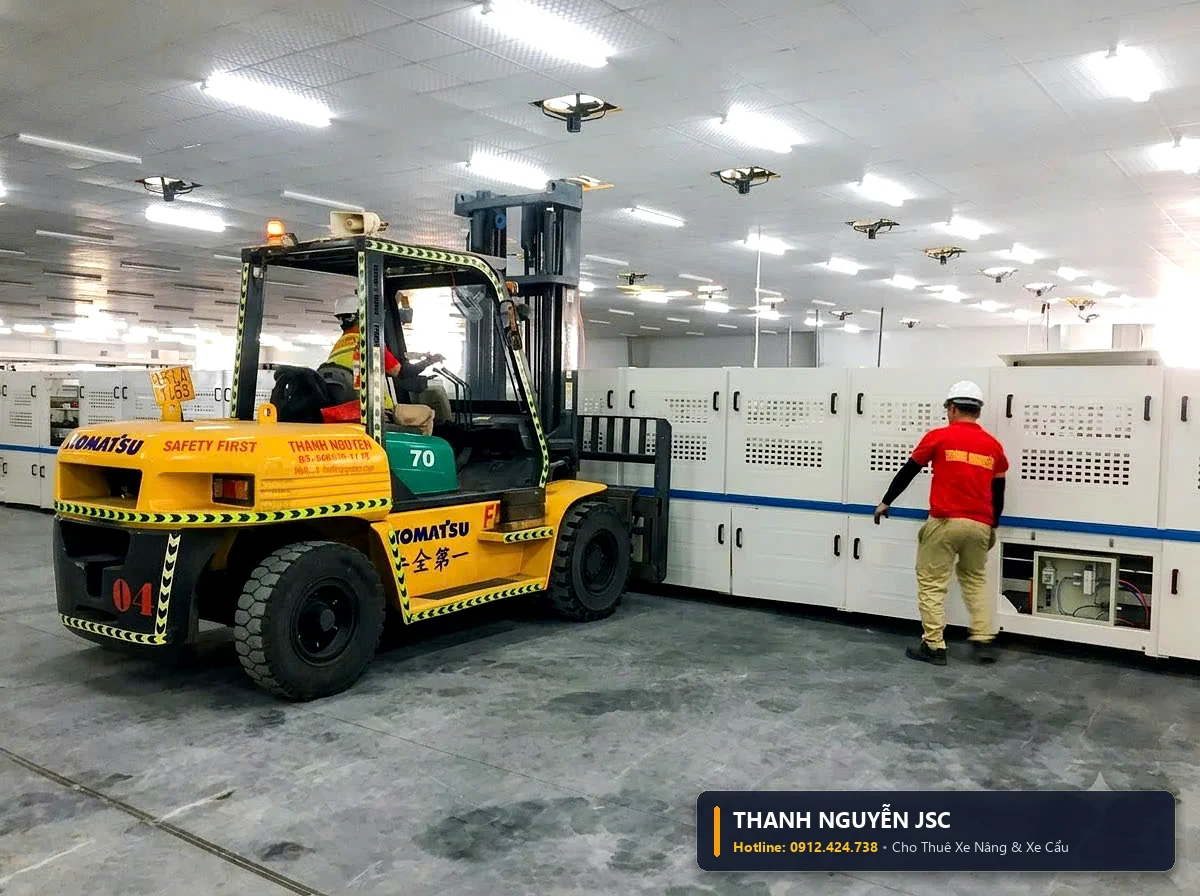 Xe nâng hàng Komatsu áp sát định vị khối thiết bị tự động vào dây chuyền nhà xưởng
